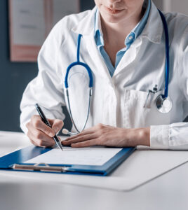 Doctor sitting at desk and writing a prescription for her patient in Ontario Canada