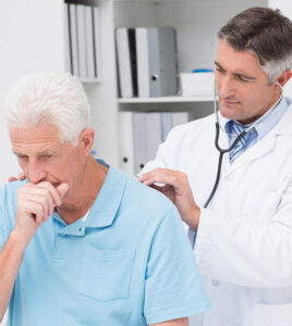 Male doctor examining coughing senior patient in clinic in Peterborough Canada