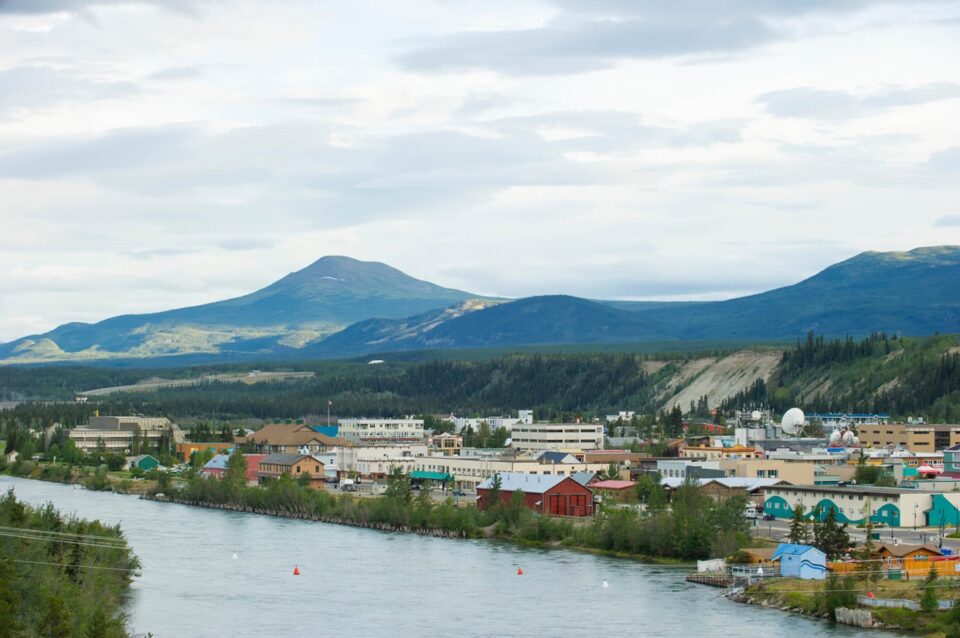 A river flows through a town with majestic mountains in Yukon, Canada